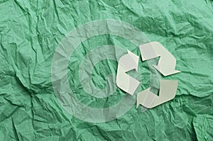 Top view of eco sign, recycling symbol on the crumpled paper.Empty space for text photo