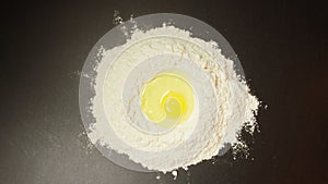 TOP VIEW: Egg in a flour on black table