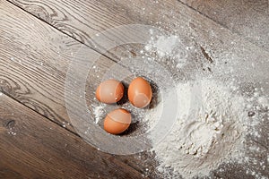 Top view of the egg, flour, a glass of fresh milk, cooking dough on the background of a wooden table. Flat lay, copy space