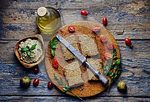 Top view of eggplant tahini dip, bread, cherry tomato and olive oil on vintage wooden table. Mediterranean cuisine still life.