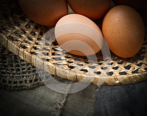 Top view of eggs in a straw basket on a natural linen napkins and a rustic wooden background
