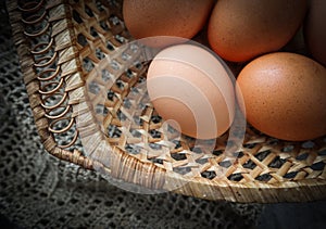 Top view of eggs in a straw basket on a natural linen napkins and a rustic wooden background