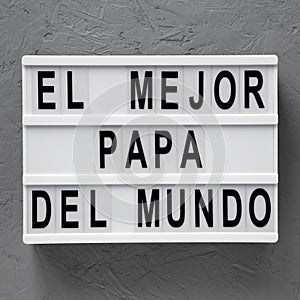 Top view, `El Mejor Papa Del Mundo` words on modern board over concrete surface. Overhead, from above, flat lay. Father`s day photo