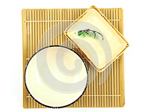 Top view, empty beige ceramic bowl and small plate on bamboo mat isolated on a white background.