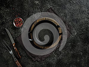 Top view of an empty black cast iron frying pan on a wooden board and a cloth towel