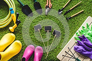 top view of empty blackboards surrounded by rubber boots, gardening equipment and protective gloves