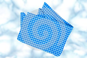 Top view of a empty blue and white checkered kitchen cloth, textile, tablecloth or napkin on blurred abstract light blue white