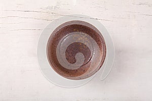 Top view of empty brown plate put on white wood table