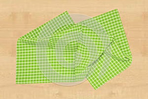Top view of a empty green and white checkered kitchen cloth, textile, tablecloth or napkin on blurred light wooden background.