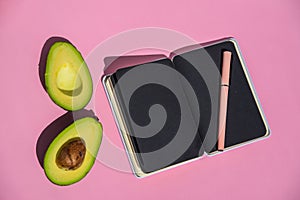 Top view An empty notepad and sliced avocado on a pink background Top view.