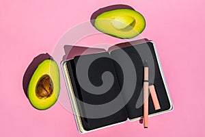 Top view An empty notepad and sliced avocado on a pink background Top view.