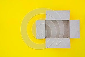 Top view of empty open brown paper cardboard box isolated on yellow background, copy space, flat lay