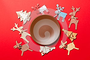 Top view of empty plate and New Year decorations on colorful background. New year serving for festive dinner. Reindeer and