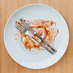 Top view of empty plate, tomato sauce smeared on finished plate.