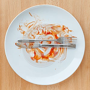 Top view of empty plate, tomato sauce smeared on finished plate.