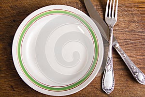 Top view of empty plate and vintage cutlery on wooden board