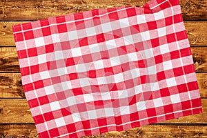 Top view of a empty red and white checkered kitchen cloth, textile, tablecloth or napkin on blurred wooden background. Template