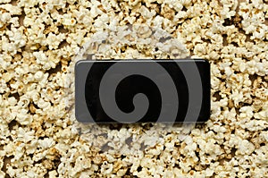 Top view of empty screen of smartphone on the sweet fresh popcorn photo