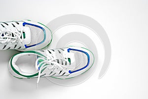 Top view of empty white sneakers with blue and green decorations, setting on left side of the shoot.