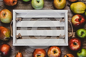 top view of empty wooden box surrounded by pears and apples