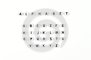 Top view of the English alphabet made of white beads with the English alphabet scattered on a white background with
