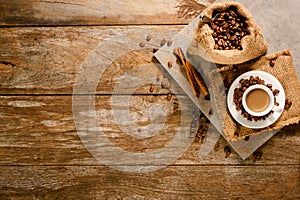 Top view of espresso on grey tile with coffee bean bag and cinnamon on wood background