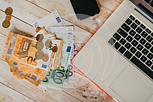 Top view euro banknotes and coins and the part of the laptop on
