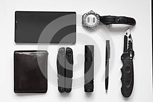 Top view of everyday  carry  EDC  items for men in black color on white background -  flashlight, watch,  multi tool  multitool