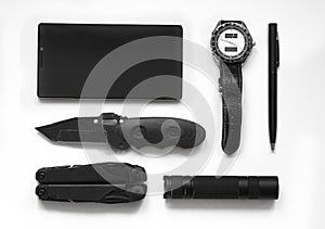 Top view of everyday  carry  EDC  items for men in black color on white background -  flashlight, watch,  multi tool  multitool