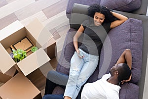 Top view excited African American couple taking break, unpack boxes