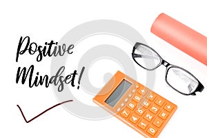 Top view of eyeglasses, calculator and colored paper over white background written with POSITIVE MINDSET
