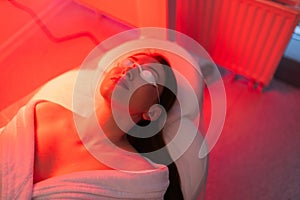 Top view face of female client lying during non-invasive type of phototherapy. Closeup of woman patient in protective photo
