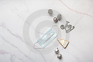 Top view of face mask and Christmas ornaments on white marble surface-new normal concept