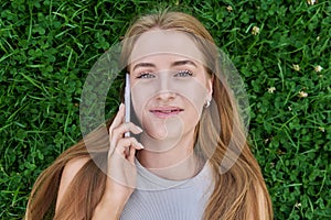 Top view face of teenage girl talking on mobile phone lying on green grass