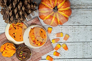 Top view of fall food arrangement with candy corn, sugar cookies and autumn cupcakes