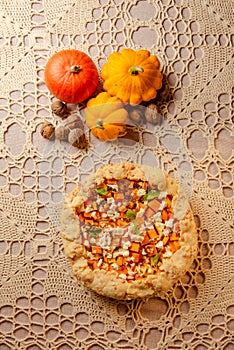 top view fall still life with harvest - pumpkin and homemade galette, pumpkin open pie on on beige knitted tablecloth