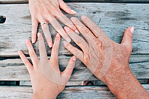Top view of family members' hands on a wooden table, three generations of women