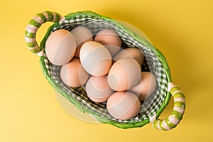 Top view. Farm brown eggs in a wicker basket lined with checkered fabric. Copy space