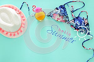 Top view of fashion female swimsuit bikini and white fedora hat on mint wooden background. Summer beach vacation concept.