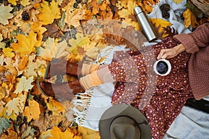 Top view of fashionable vintage style girl holding cup with coffee in autumn park