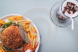 Top view of a fast food meal featuring a hamburger, french fries, and a beverage on a table.