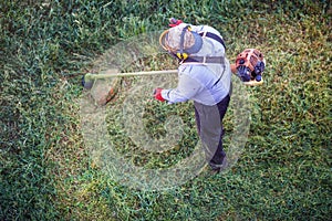 Top view fat dirty lawnmover man worker cutting dry grass with lawn mower