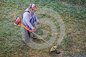 Top view fat dirty lawnmover man worker cutting dry grass with lawn mower