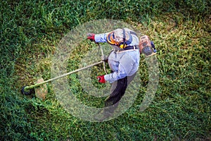 Top view fat dirty lawnmover man worker cutting dry grass with lawn mower photo