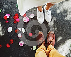 Top view of feet of a young couple with little beautiful red rose petal on the ground