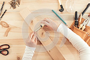 Top view of female carpenter hands working on desk