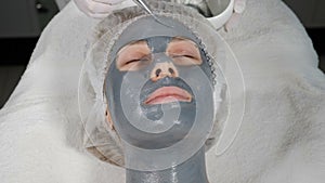 Top view of female client getting facial beauty treatment. Applying facial mask to face skin at beauty salon.Spa therapy