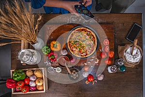 Top view, female cook using smartphone Take a photo of the pizza on the plate