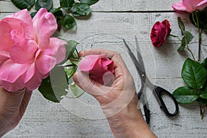 Top view of female decorator arranging roses on the wooden table photo