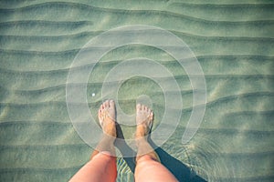 Top view of female feet under clear water.